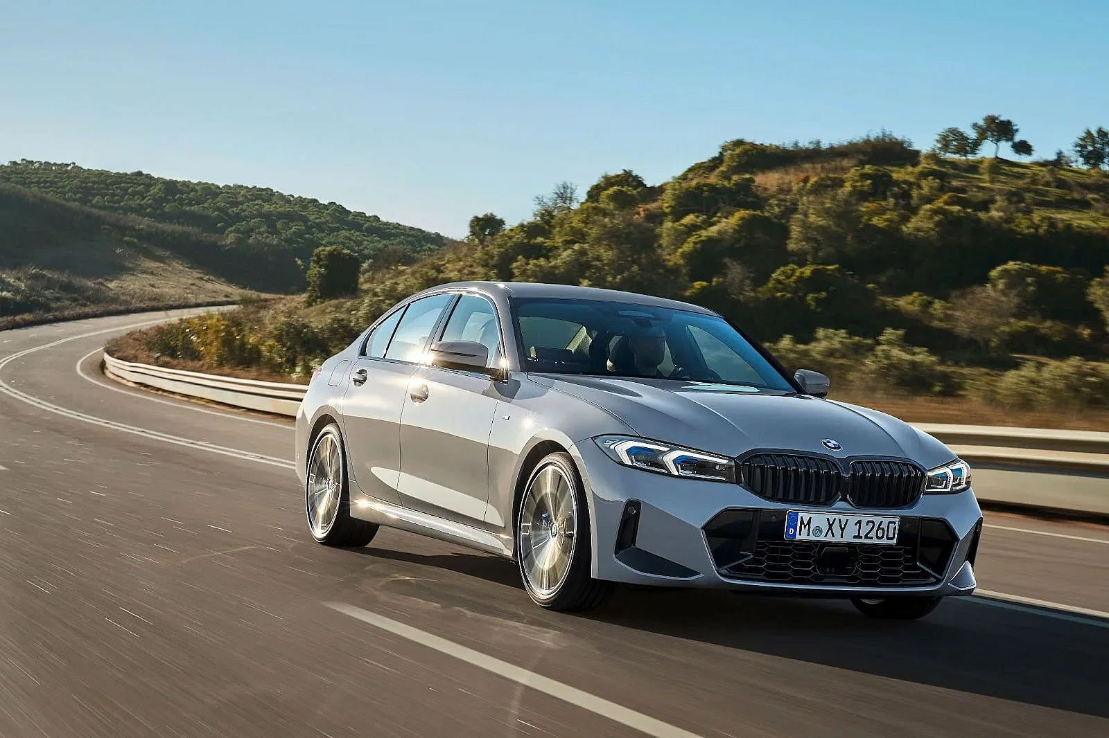 gray 2024 BMW 330i driving down a road